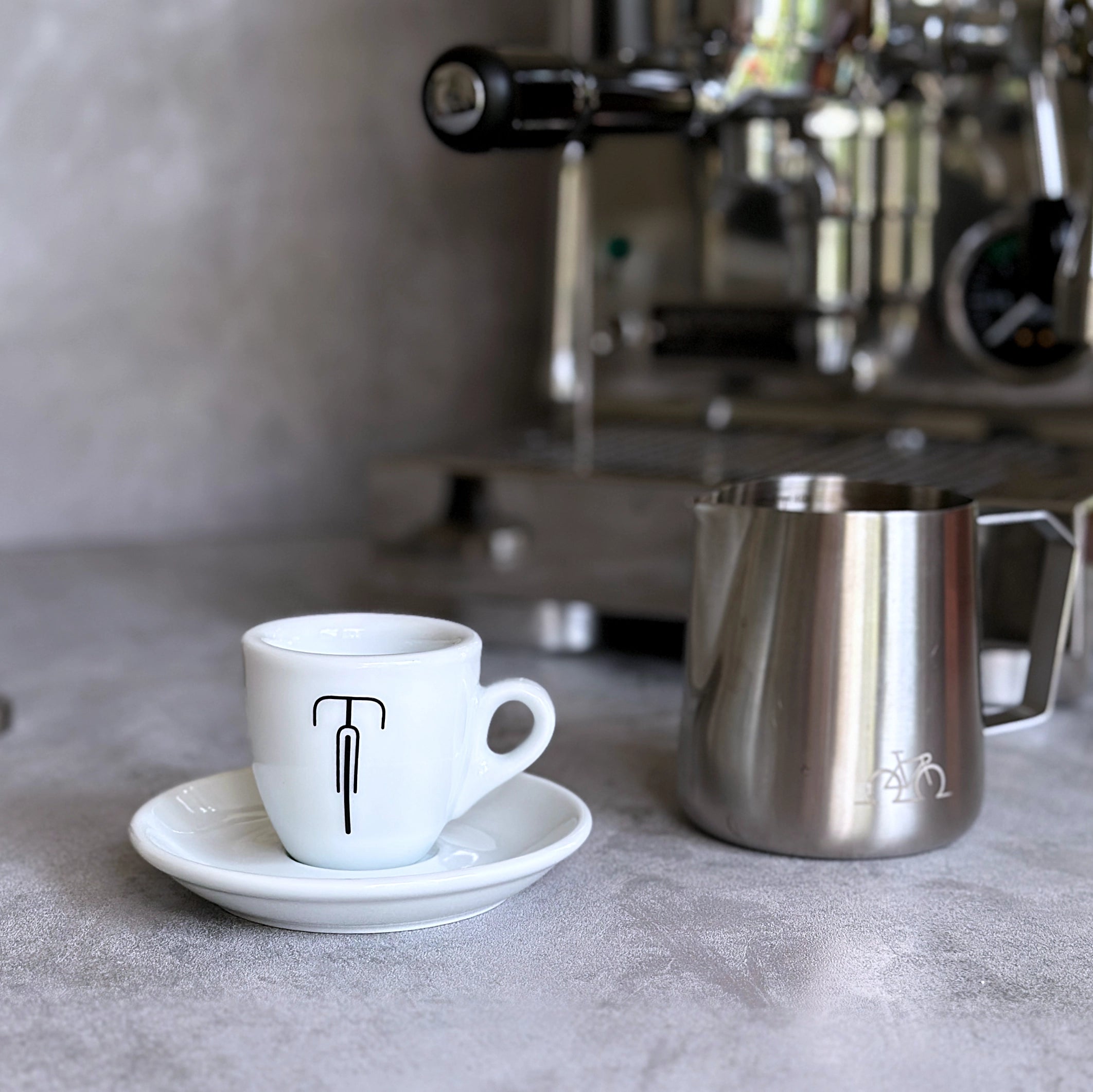Espresso-Tasse mit Rennrad-Motiv vor einer Siebträgermaschine