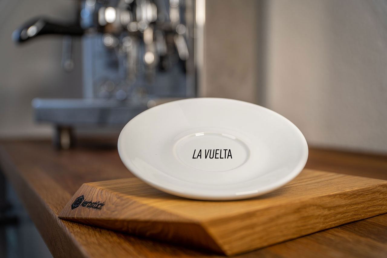 Eine weiße Untertasse mit dem Schriftzug „La Vuelta“.