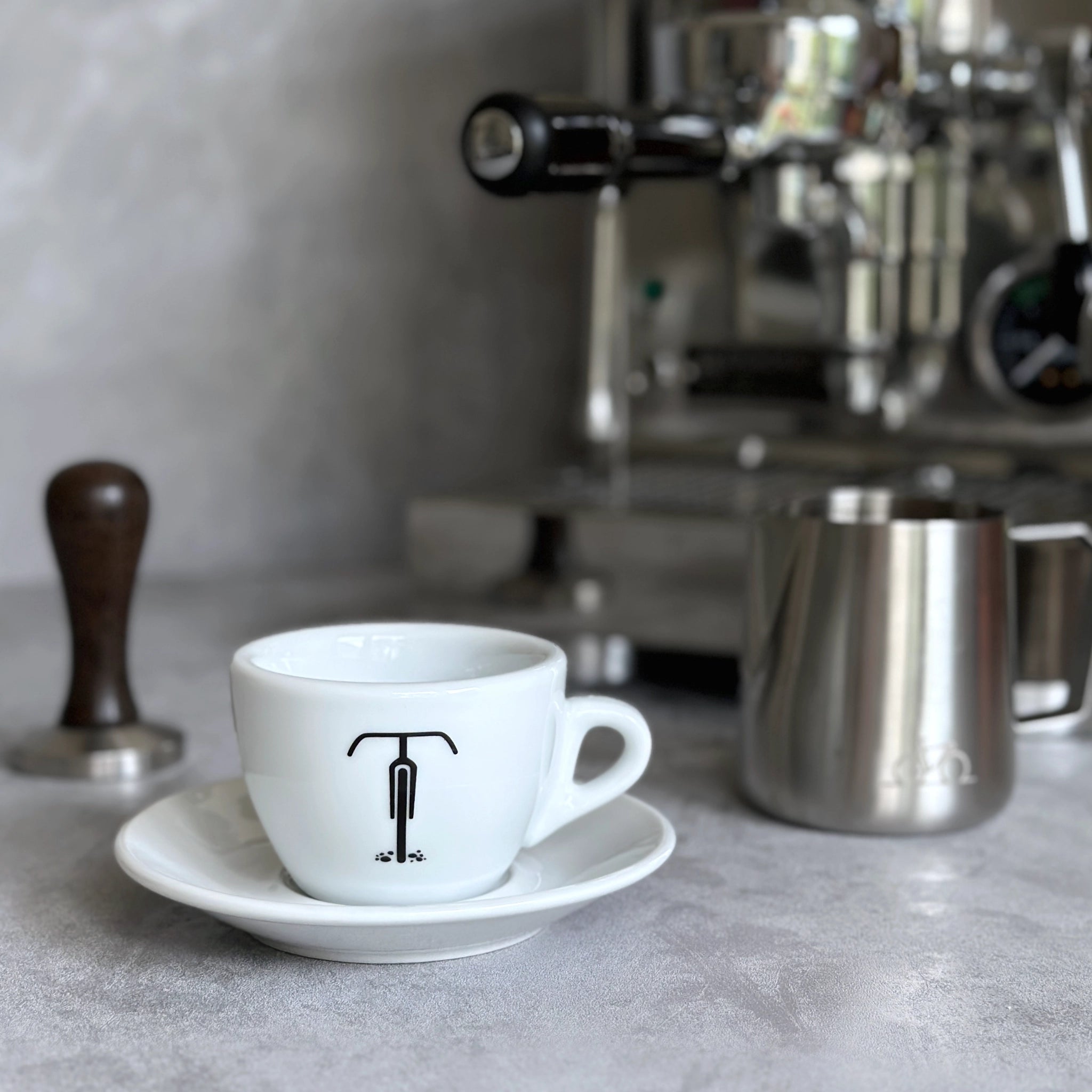 Cappuccino-Tasse mit Gravel-Rad-Motiv  vor Siebträgermaschine