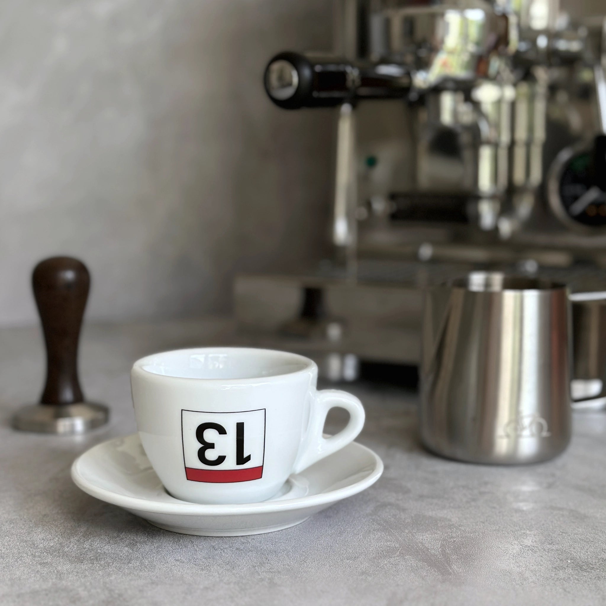 Cappuccino-Tasse mit Radsport-Print Lucky 13 vor Siebträgermaschine