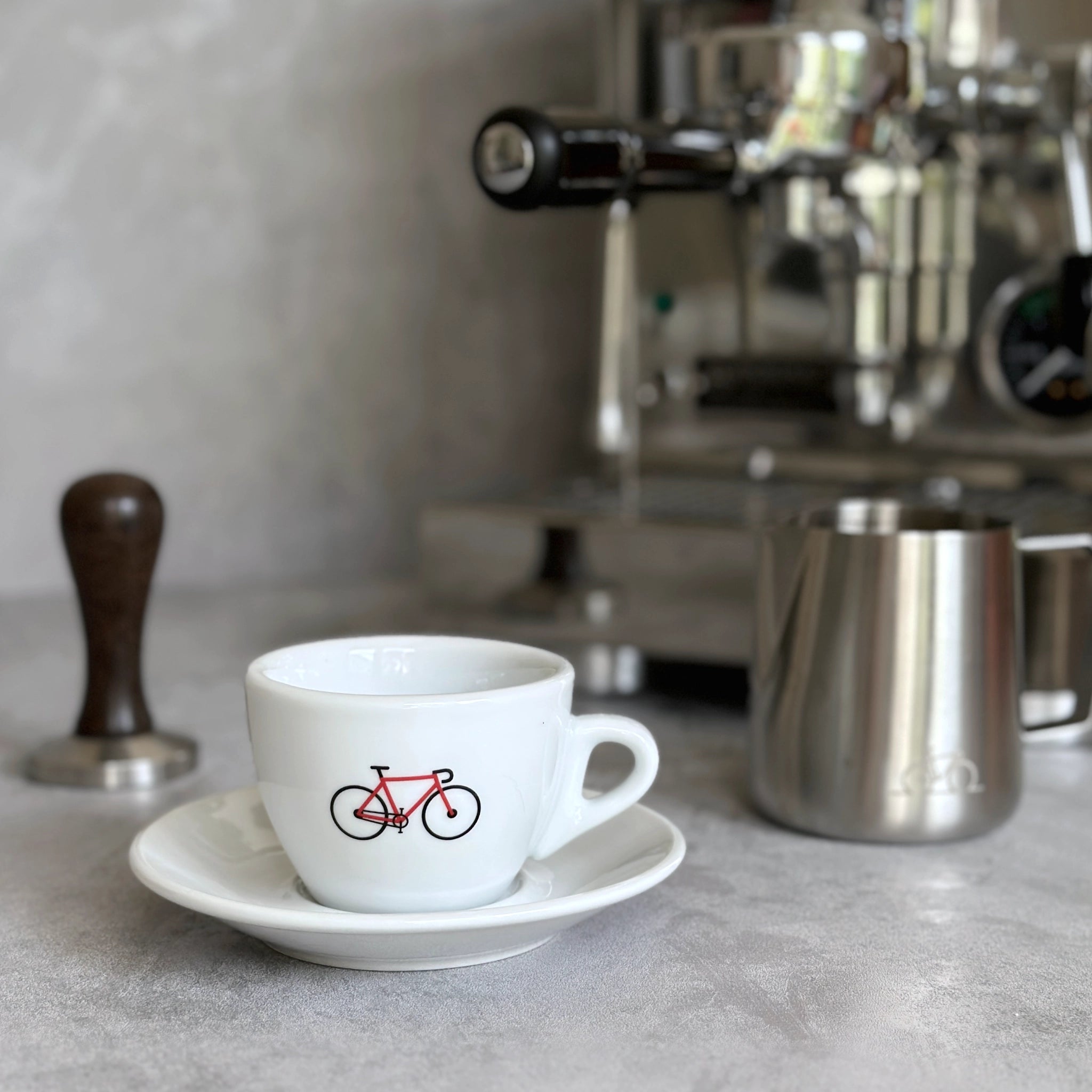 Cappuccino-Tasse mit Rennrad-Motiv in rot vor einer Siebträgermaschine