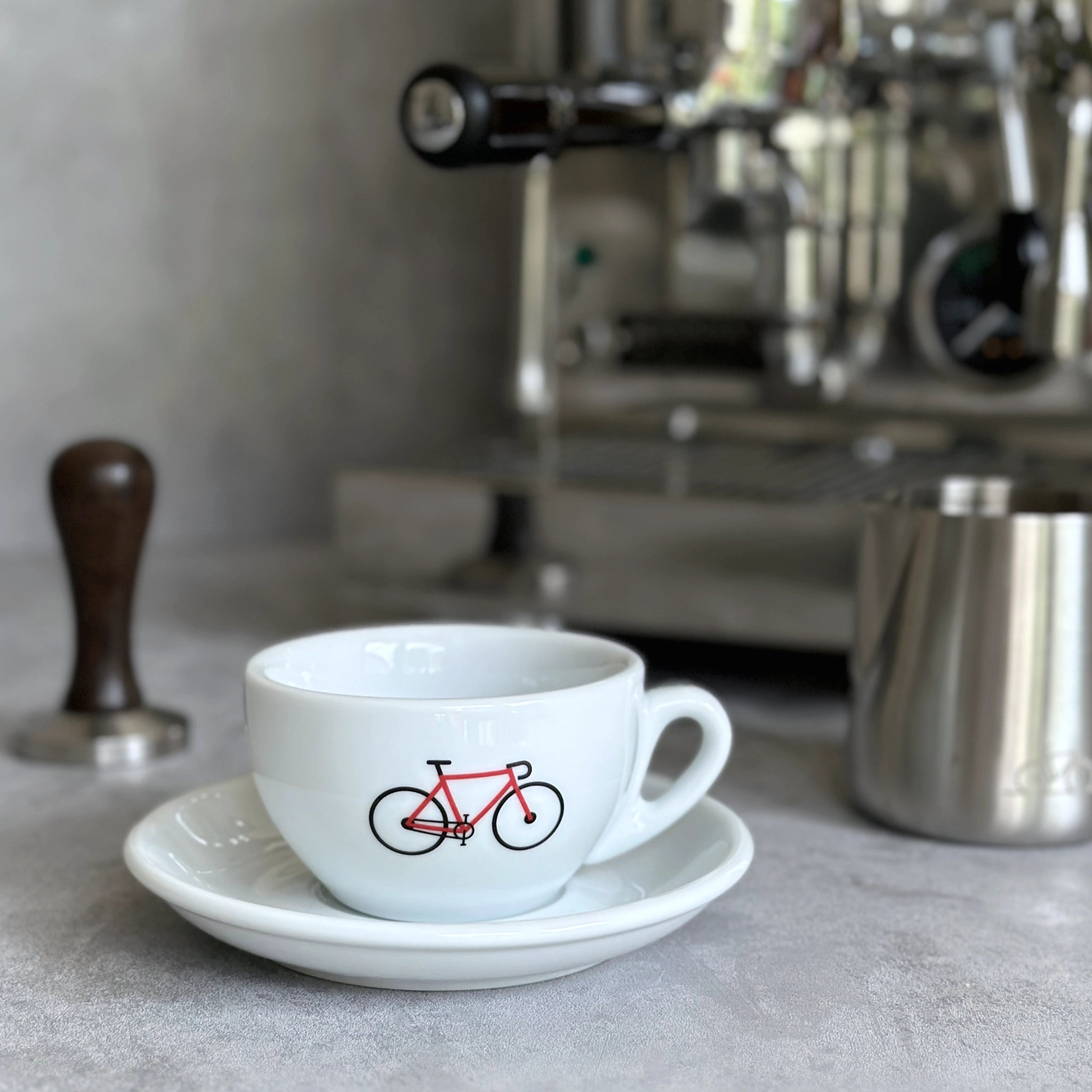 Cappuccino Grande Tasse mit Rennrad-Motiv in rot vor Siebträgermaschine