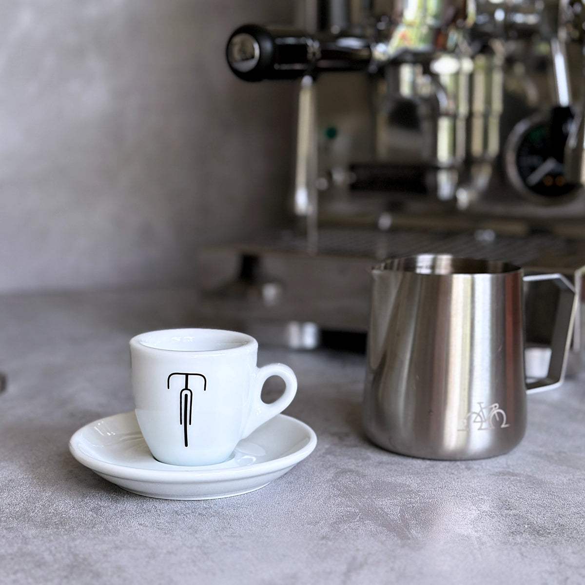 Espresso-Tasse mit Rennrad-Motiv vor einer Siebträgermaschine