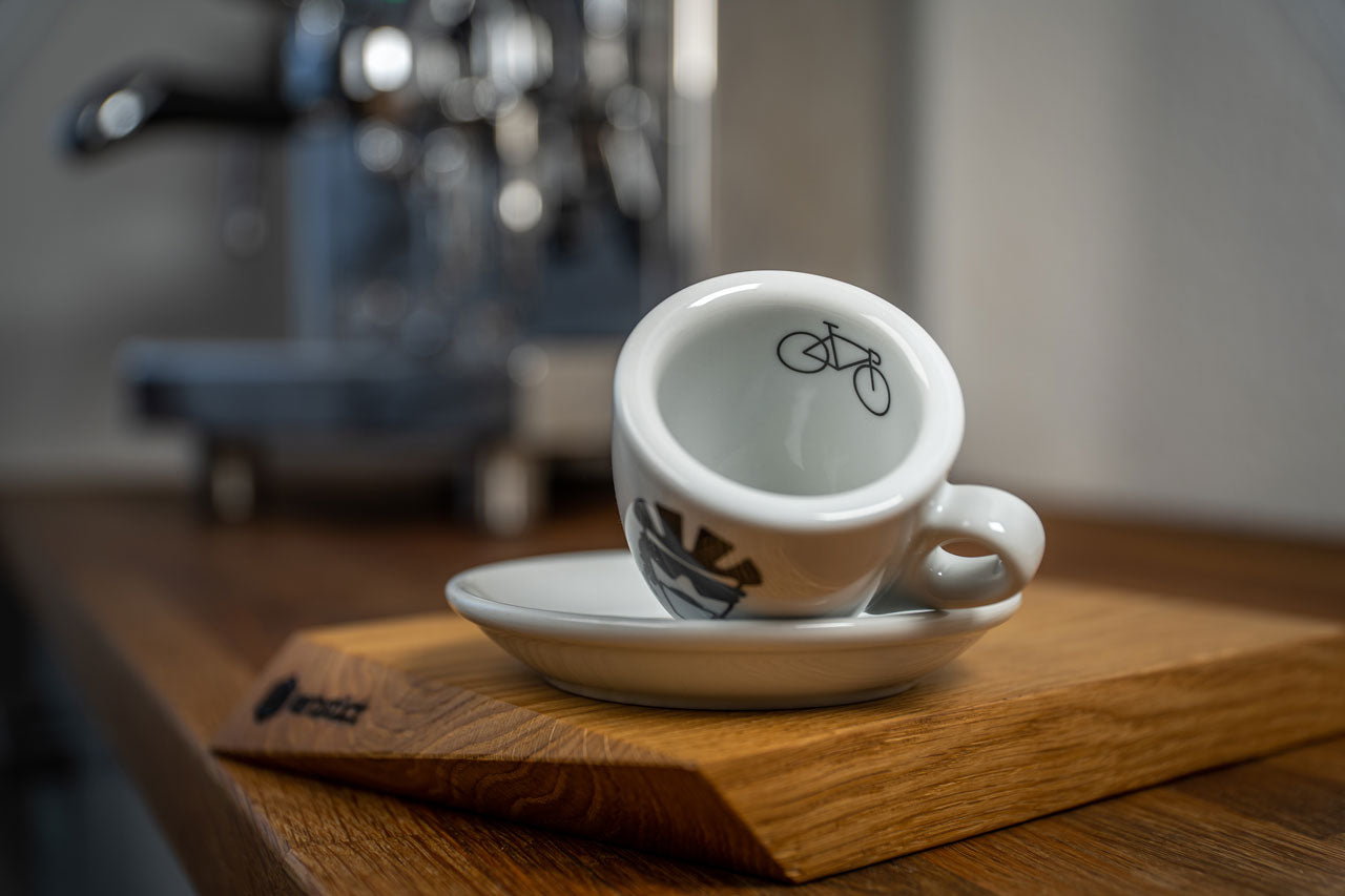 Eine Espresso-Tasse liegt auf der Seite, auf dem inneren Tassenrand ist ein Rennrad abgedruckt.