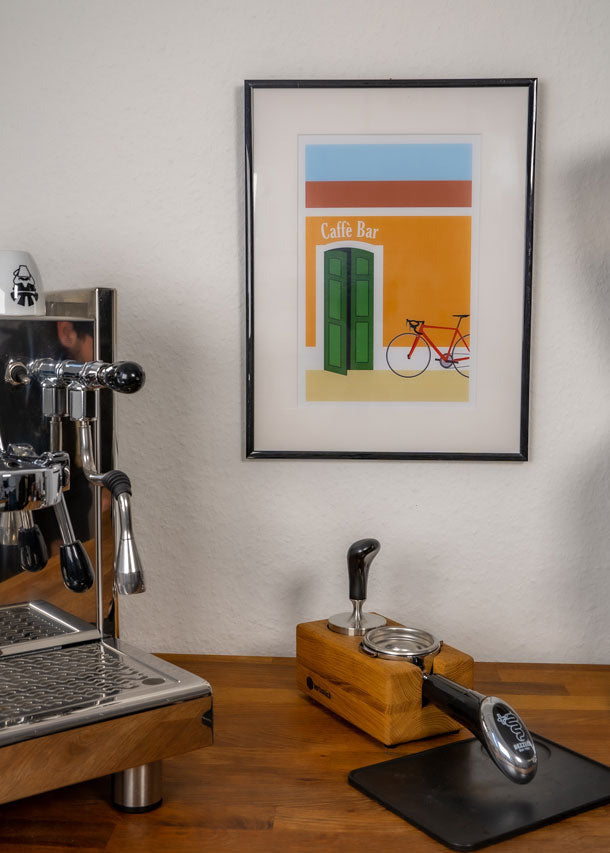 Das Poster "Caffè Bar" hängt im Bilderrahmen an der Wand zwischen einer Kaffeemaschine und einer Kaffeemühle.