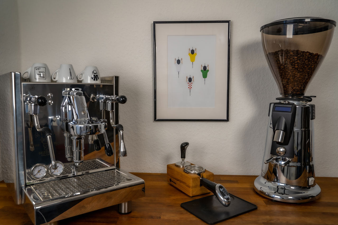 Das Poster "Helden der Landstraße" hängt im Bilderrahmen an der Wand zwischen einer Kaffeemaschine und einer Kaffeemühle.